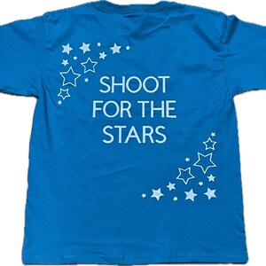 May include: A bright blue t-shirt with a white graphic that says "Shoot for the Stars" and a design of white stars.