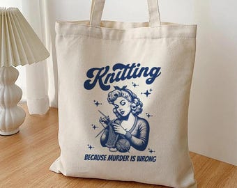 May include: A white canvas tote bag with a blue graphic of a woman knitting. The text on the bag reads "Knitting because murder is wrong."