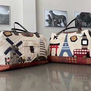 Puede incluir: Dos bolsas de viaje acolchadas con diseños diferentes. La bolsa de la izquierda tiene un molino de viento y flores, mientras que la bolsa de la derecha tiene una Torre Eiffel, un autobús de dos pisos rojo y un templo japonés.