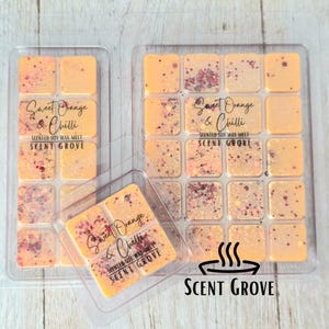 May include: Three clear plastic containers of Sweet Orange & Chilli scented soy wax melts. The wax melts are orange with red and gold glitter. The text "Sweet Orange & Chilli" and "Scent Grove" are printed on the containers.