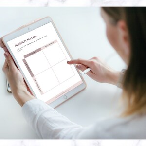 Op de afbeelding: Een digitale tablet met een "Prioriteitenmatrix" sjabloon. Het sjabloon is verdeeld in vier kwadranten: "Dringend", "Niet Dringend", "Belangrijk" en "Niet Belangrijk". Een stylus raakt het scherm aan. De tablet wordt door een persoon vastgehouden.