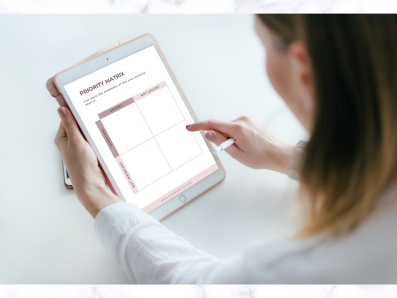 Op de afbeelding: Een digitale tablet met een "Prioriteitenmatrix" sjabloon. Het sjabloon is verdeeld in vier kwadranten: "Dringend", "Niet Dringend", "Belangrijk" en "Niet Belangrijk". Een stylus raakt het scherm aan. De tablet wordt door een persoon vastgehouden.