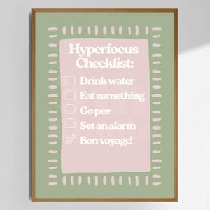 Puede incluir: Una lámina enmarcada con fondo verde salvia y un rectángulo rosa en el centro. El texto dice Hyperfocus Checklist: Drink water, Eat something, Go pee, Set an alarm y Bon voyage! con un pequeño icono de un cohete.
