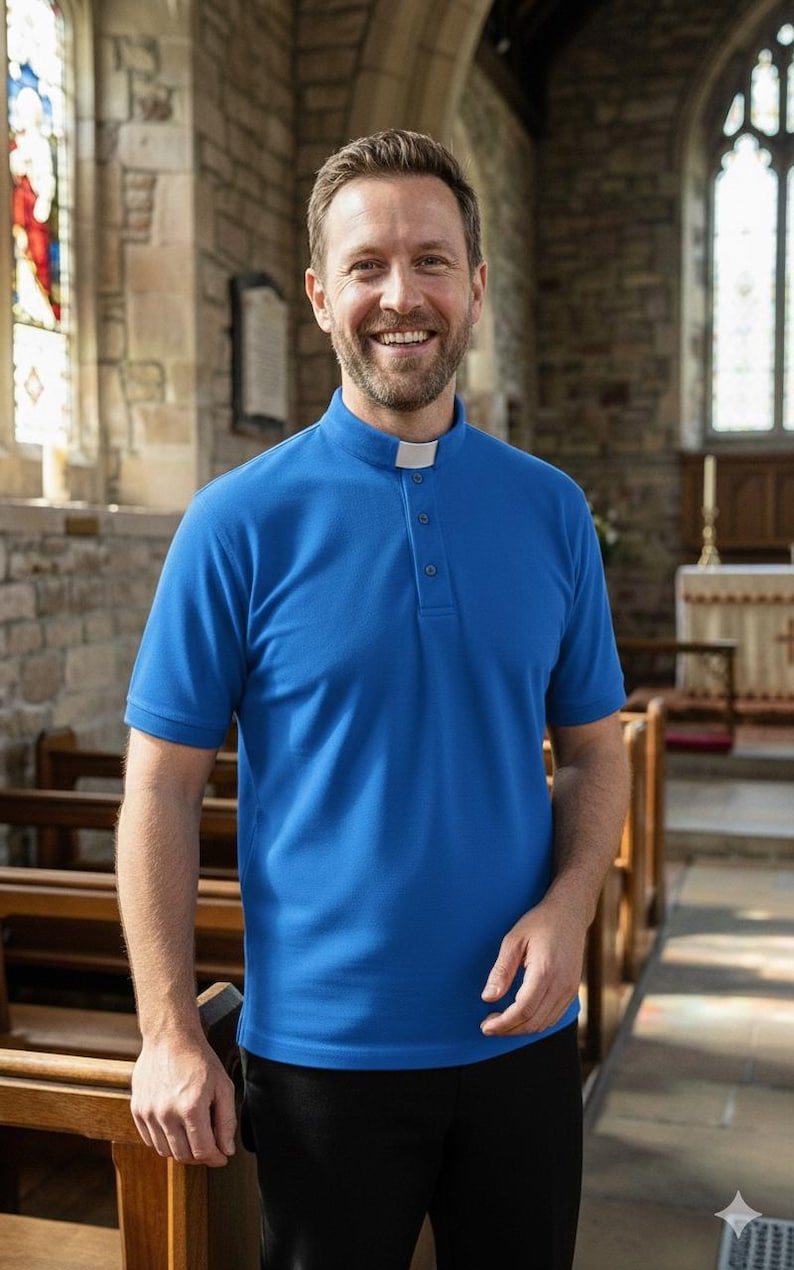 Op de afbeelding: Een felblauw overhemd met korte mouwen voor geestelijken, voorzien van een opstaande kraag met een wit inzetstuk en een gedeeltelijke knoopsluiting aan de voorzijde. Het overhemd is gemaakt van effen stof en gecombineerd met een zwarte broek.