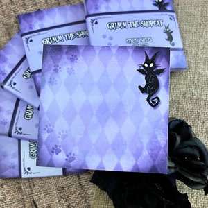 May include: Purple sticky notes with a diamond pattern and paw prints. The notes feature the text "Grimm the Shopcat" and a black cat silhouette. A stack of similar notes is visible.