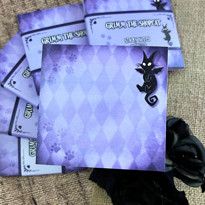 May include: Purple sticky notes with a diamond pattern and paw prints. The notes feature the text "Grimm the Shopcat" and a black cat silhouette. A stack of similar notes is visible.