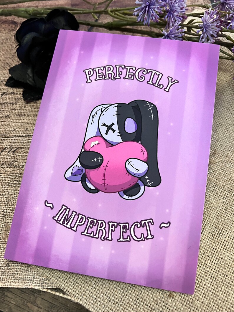 May include: A purple background with a white and black stitched plush toy holding a pink heart. The text "PERFECTLY IMPERFECT" is written in a stylized font.
