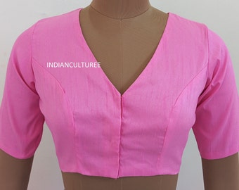 Rose pink solid saree blouse has a V-neck, short sleeves, and a stylized front with front hook and eye closure
