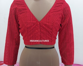 Puede incluir: Blusa roja bordada con cuello en V y mangas tres cuartos. La blusa tiene un cierre de botón en el cuello y una banda negra en la cintura.