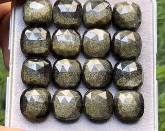 Pode incluir: Uma coleção de dezasseis pedras preciosas de obsidiana dourada, cada uma com uma forma almofadada facetada. As pedras estão dispostas numa grelha dentro de uma bandeja branca, mostrando o seu brilho metálico refletor. As pedras são de cor verde-oliva escura.