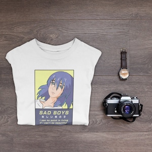 May include: White t-shirt with a graphic print of an anime character with blue hair. The text "SAD BOYS 悲しい男の子 I see no point in living if I can't be beautiful" is printed below the image.