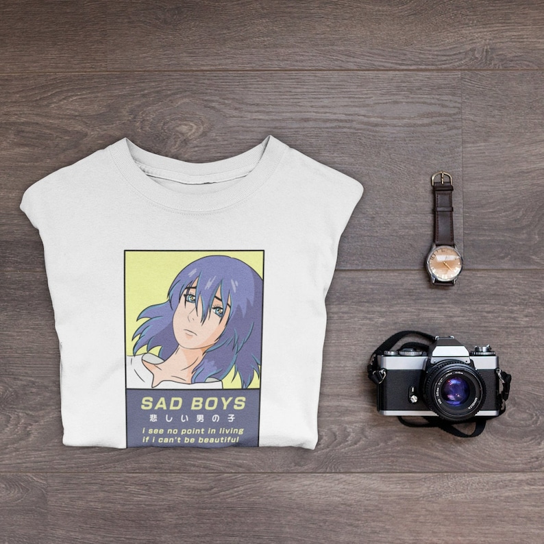 May include: White t-shirt with a graphic print of an anime character with blue hair. The text "SAD BOYS 悲しい男の子 I see no point in living if I can't be beautiful" is printed below the image.
