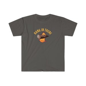 May include: A dark gray t-shirt with a cartoon character holding a log. The character is on fire and the text "HANG IN THERE" is written in a yellow circle around the character.
