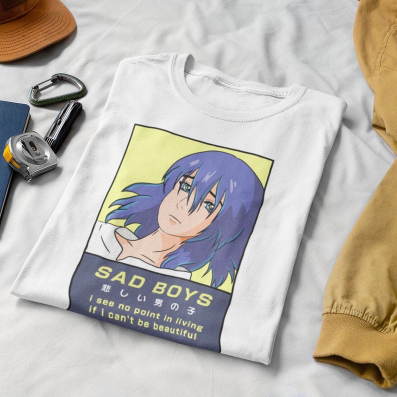 May include: White t-shirt with a graphic of a blue-haired anime character. The text "SAD BOYS 悲しい男の子 i see no point in living if i can't be beautiful" is printed on the shirt.
