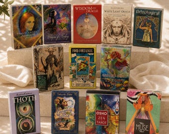 May include: A collection of twelve rectangular tarot and oracle card decks arranged in three rows. The boxes feature diverse colorful illustrations, including figures, nature scenes, and abstract designs, with titles such as Thoth, The Muse, and Wisdom of the Oracle printed on the front covers.