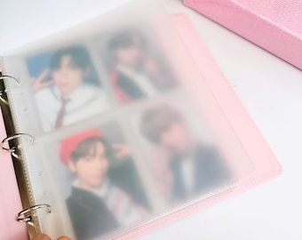 May include: Pink binder with clear plastic sleeves for holding photos or cards. The binder has a ring mechanism and is closed.