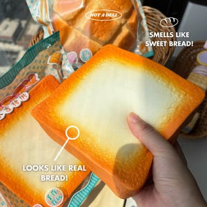 May include: A close-up of a slice of bread with a white centre and orange crust. The text "LOOKS LIKE REAL BREAD!" is visible. The text "SMELLS LIKE SWEET BREAD!" is also visible. The bread is in a clear plastic bag with the text "NOT A DELI".