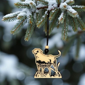 A Christmas Tree with pinecones and berries featuring a wood four layered Labrador Retriever Ornament with a duck hunting scene engraved on it.