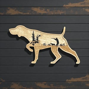 May include: Wooden wall art in the shape of a dog, featuring a hunting scene silhouette. The dog's body is light brown, with a dark brown background. The scene inside the dog includes trees, a hunter, and other dogs.
