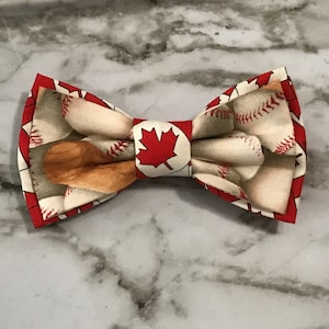 May include: A red, white, and brown bow tie with a baseball and maple leaf pattern.