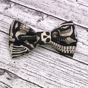 May include: A black bow tie with a white skeleton and skull pattern.