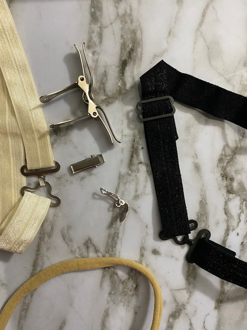 May include: Two sets of white and black elastic straps with metal clips. The straps are used to hold up socks or stockings.