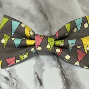 May include: A gray bow tie with a colorful pattern of flags and light bulbs.