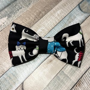 May include: A black bow tie featuring a white and blue pattern of dogs. The dogs are wearing various outfits and accessories.