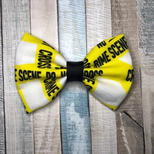 May include: A white bow tie with yellow and black "Do Not Cross Crime Scene" tape printed on it.
