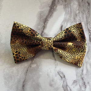 May include: A brown and yellow bow tie with a honeycomb pattern.