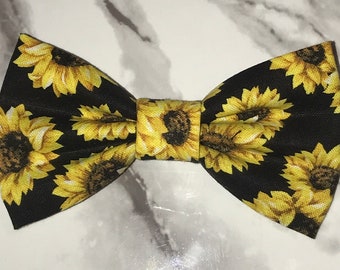 May include: A black bow tie with a yellow sunflower pattern.