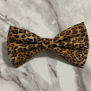 May include: A brown and black leopard print bow tie.