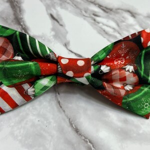 May include: A red, green and white bow tie with a Christmas bauble pattern.