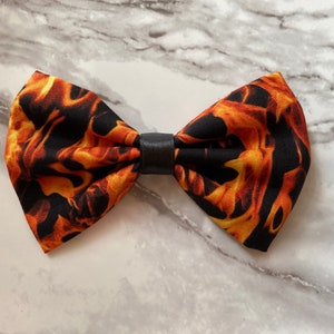 May include: A black bow tie with a flame pattern in shades of orange and yellow.