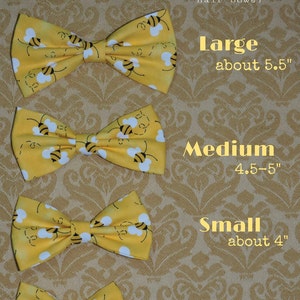 May include: Four yellow fabric bow ties with a bee pattern, displayed in order of size from largest to smallest. The sizes are labeled: Large (about 5.5 inches), Medium (4.5-5 inches), Small (about 4 inches), and Extra Small (3-3.5 inches).