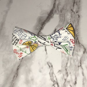 May include: A white bow tie with a pattern of handwritten mathematical equations and formulas in black, red, blue, green, and yellow.