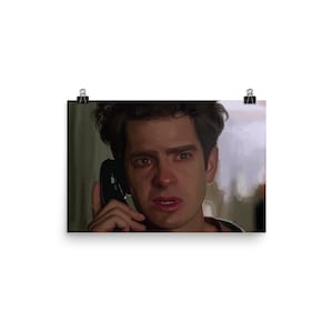 May include: A close-up portrait of a man with dark hair, wearing a red shirt, looking distressed while holding a black phone to his ear.