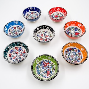May include: Set of eight small ceramic bowls with colorful floral patterns. The bowls are white with blue, red, green, orange, and black accents. The bowls are perfect for serving dips, snacks, or desserts.
