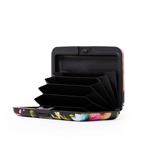 Peut inclure: Un porte-cartes en aluminium noir et &agrave; motifs floraux avec un int&eacute;rieur noir et plusieurs fentes pour cartes. Le porte-cartes est ouvert et les fentes sont visibles.