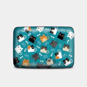 May include: A teal blue aluminum card holder with a repeating pattern of black, white, orange, and gray cats with the word "CATS" printed throughout.