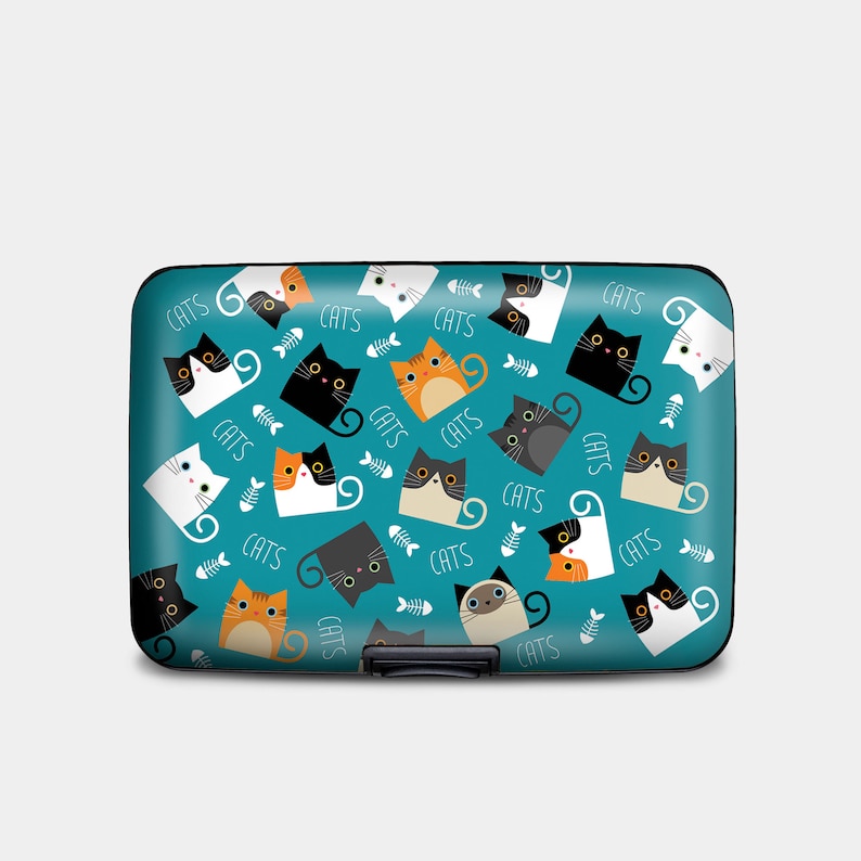 May include: A teal blue aluminum card holder with a repeating pattern of black, white, orange, and gray cats with the word "CATS" printed throughout.