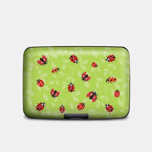 May include: A green aluminum card holder with a pattern of ladybugs on green leaves.