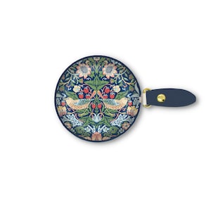 K&ouml;nnte beinhalten: Ein runder, marineblauer Handspiegel mit einem dekorativen Blumen- und Vogeldesign. Das Design zeigt V&ouml;gel, Blumen und Beeren in Gr&uuml;n-, Rosa- und Gelbt&ouml;nen. Der Griff ist aus marineblauem Leder mit einem goldfarbenen Metallakzent.