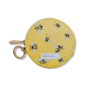 May include: A yellow round coin purse with a zipper closure and a gold key ring. The purse has a pattern of bees and honeycombs. The text "Mary Frances  Aspen" is printed on the purse.