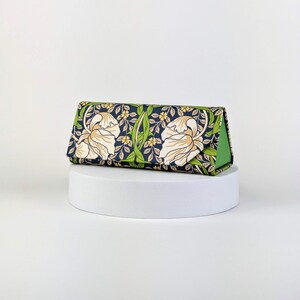 Op de afbeelding: Een driehoekig brillenetui met een bloemenpatroon. De etui heeft een marineblauwe achtergrond met cr&egrave;mekleurige bloemen, groene bladeren en kleine gele bloesems. De binnenkant is heldergroen.