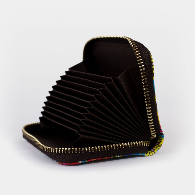 May include: A black card holder with a zipper closure and multiple card slots. The card holder is open and the slots are visible. The exterior of the card holder has a colourful floral pattern.