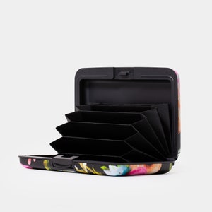 May include: A black card holder with a floral print design. The holder is open and shows multiple card slots.