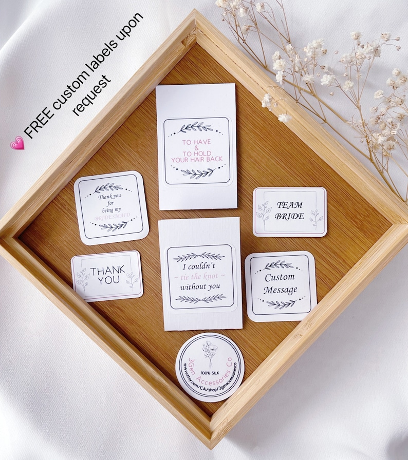 May include: A set of eight white labels with black text and floral designs. The labels include phrases like "Thank you for being my bridesmaid", "To have and to hold your hair back", "Team Bride", "I couldn't tie the knot without you", "Custom Message", and "Thank you".