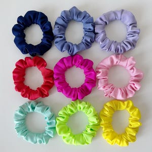 May include: Ten colorful scrunchies in various colors, including blue, purple, red, pink, green, and yellow. The scrunchies are made of soft, stretchy fabric and are perfect for holding hair in place.