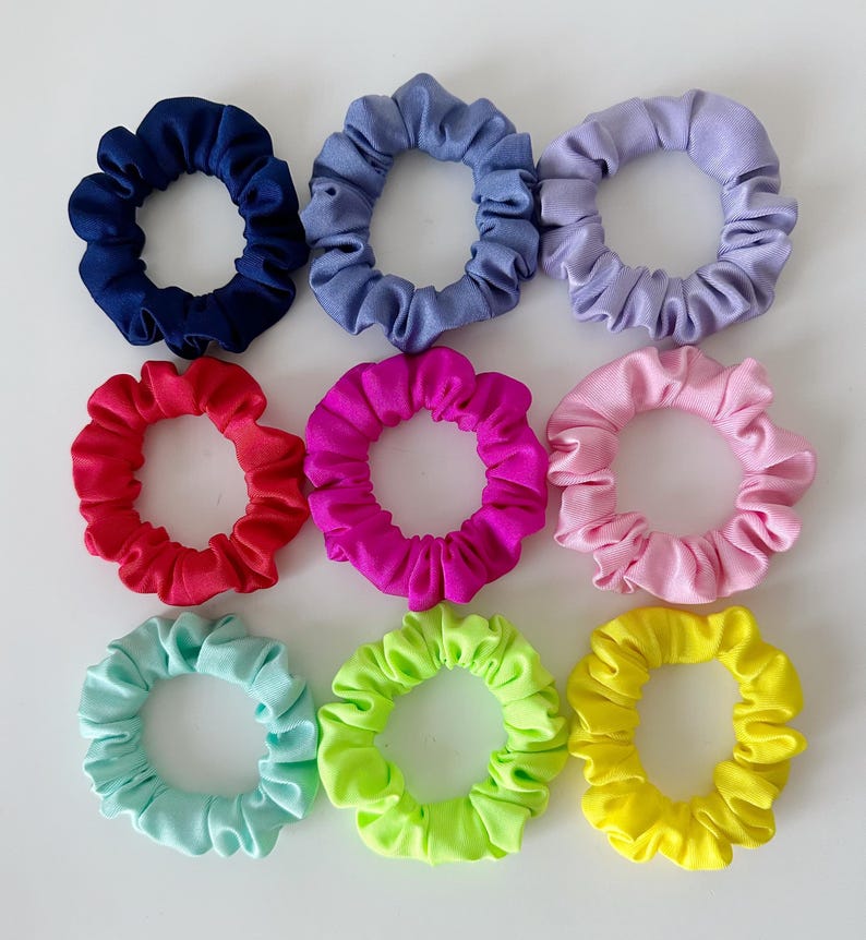 May include: Ten colorful scrunchies in various colors, including blue, purple, red, pink, green, and yellow. The scrunchies are made of soft, stretchy fabric and are perfect for holding hair in place.